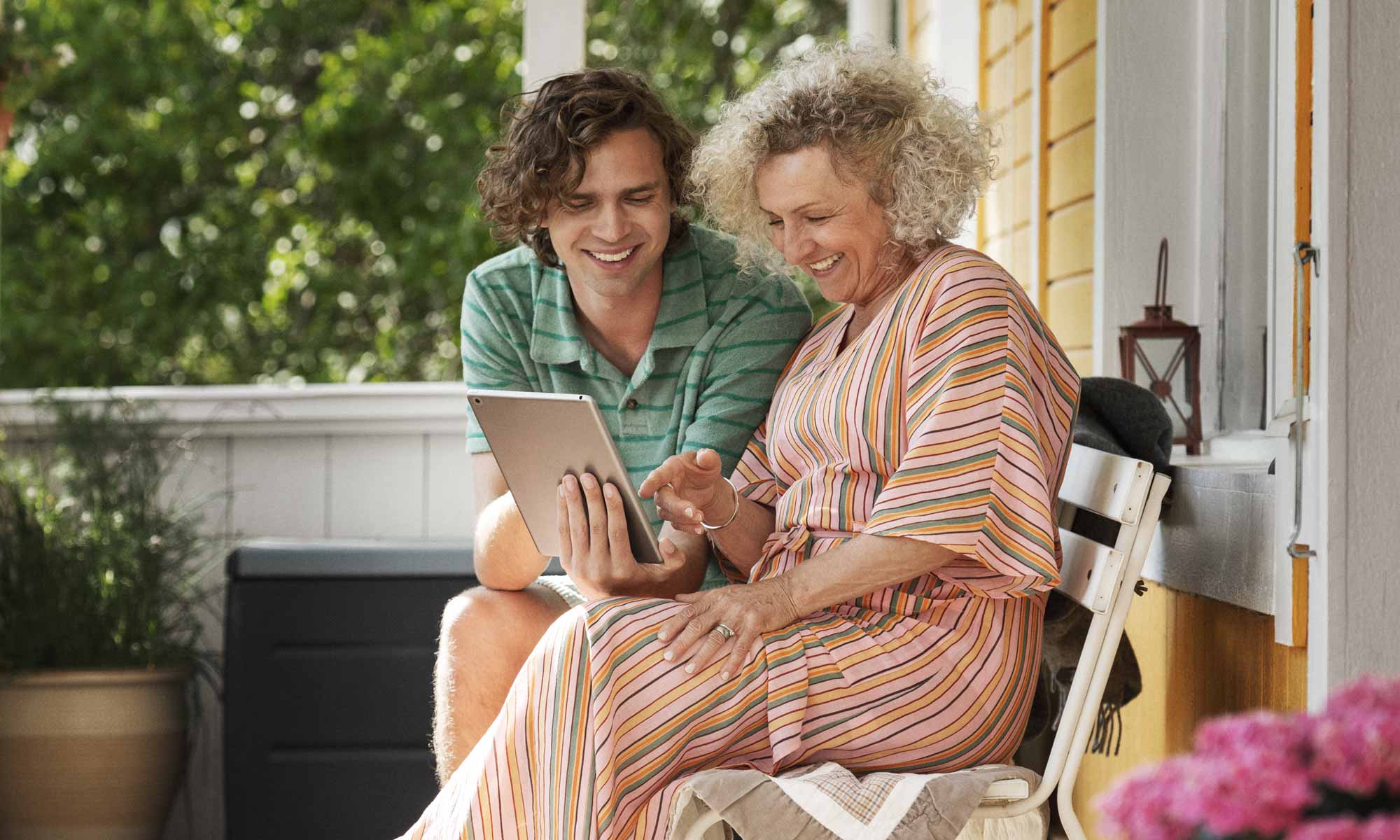 Mother and adult son looking at a laptop on the porch