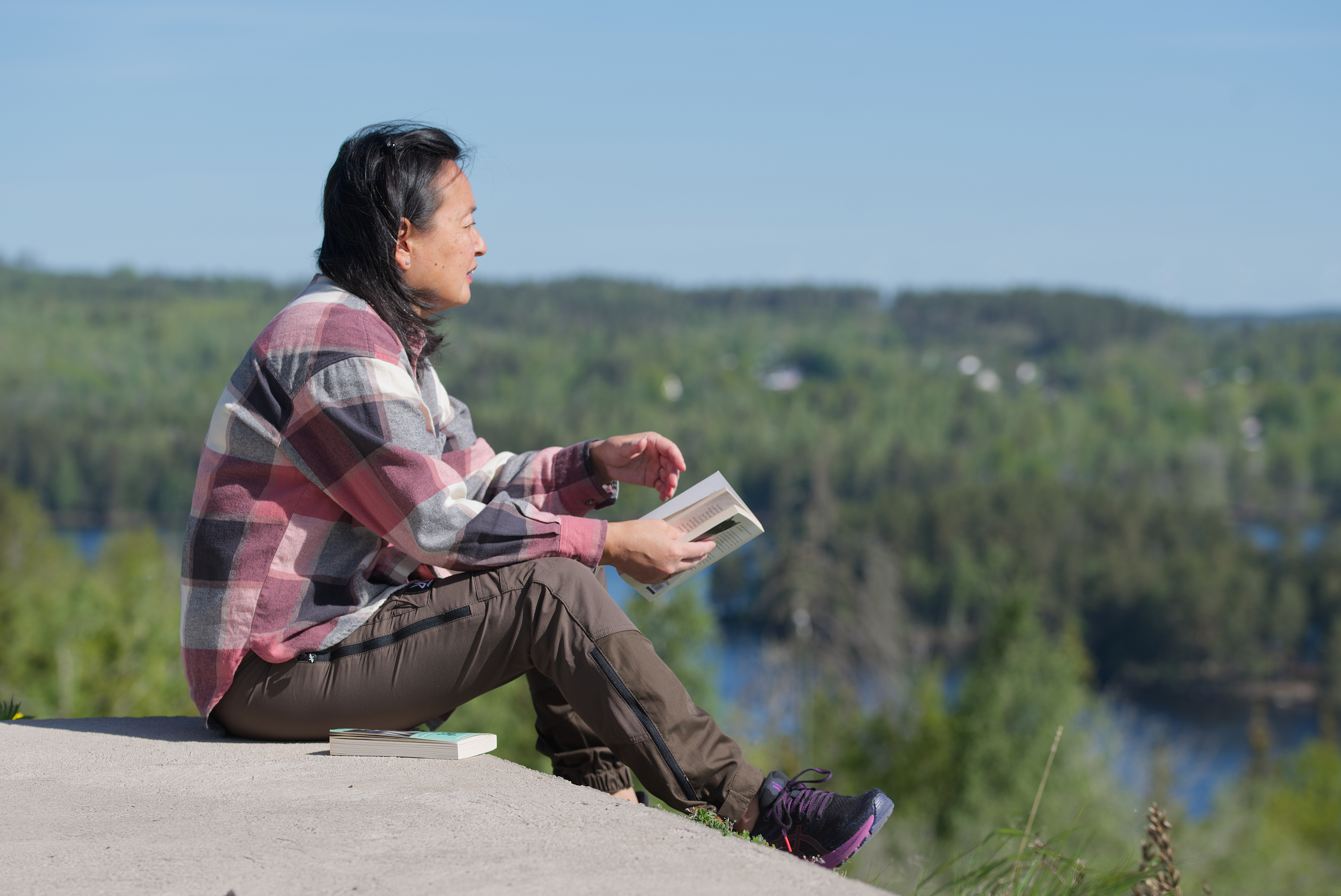 Kvinna sitter och läser på ett berg